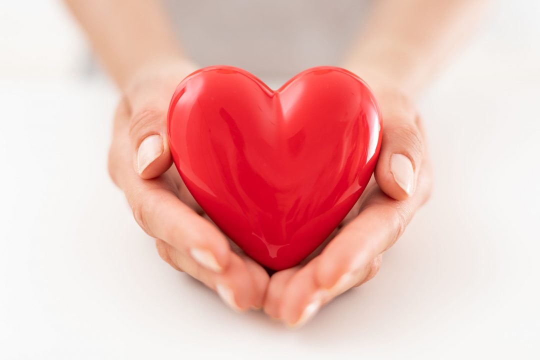 The woman is holding a red heart.